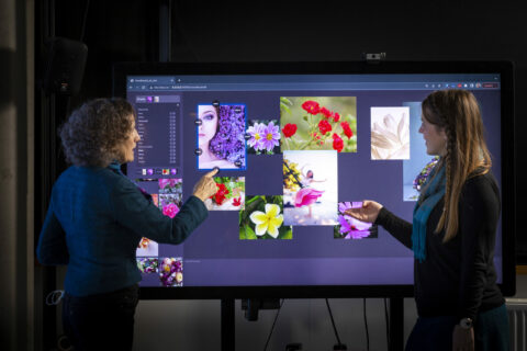 Deux femmes interagissent devant un grand écran