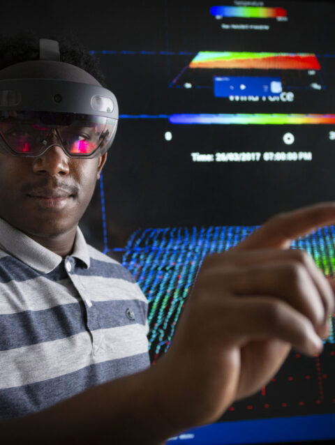 Un homme équipé d'un casque de réalité virtuelle interagit avec le contenu qui est visible en arrière plan